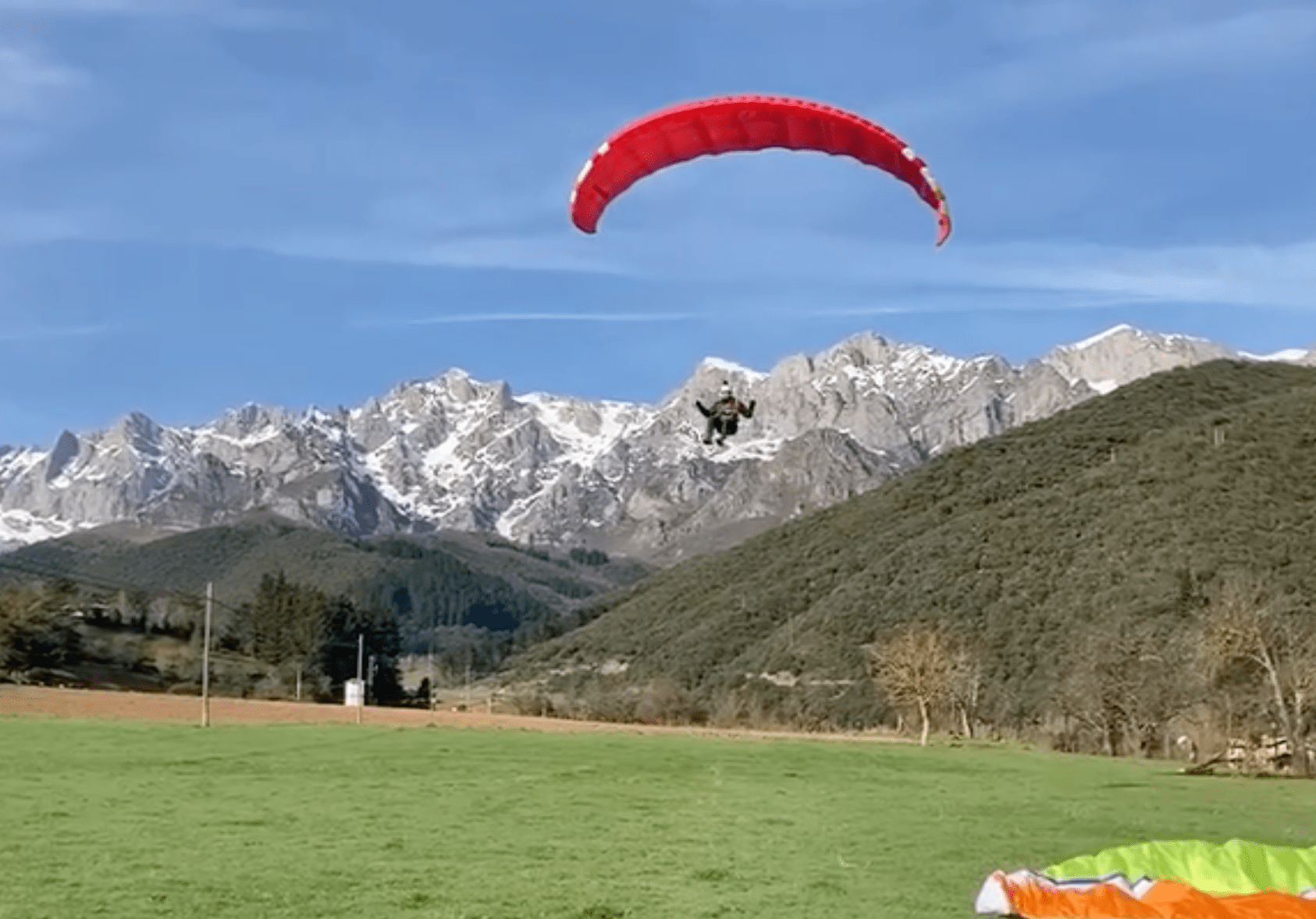 Aterrizaje de una persona en parapente en un prado
